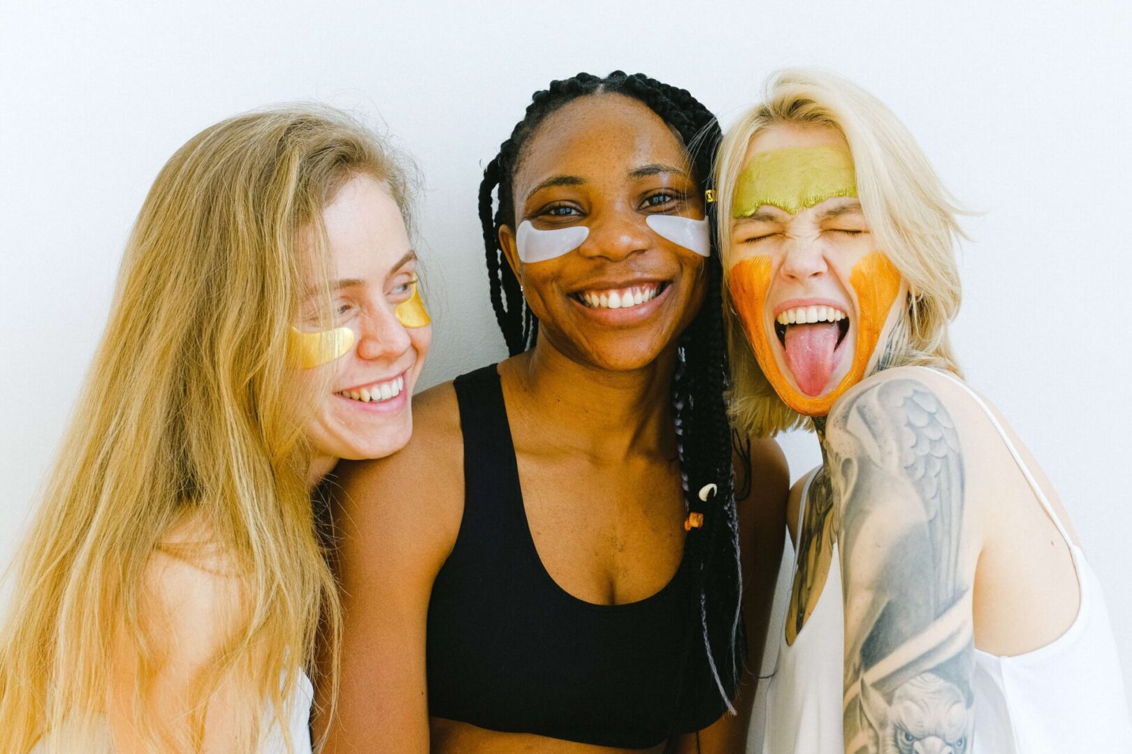 three woman smiling with skincare cosmetic on their face